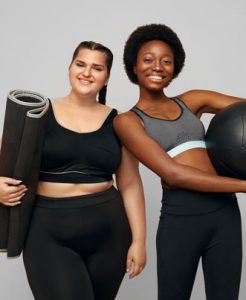 Two women holding exercise equipment smiling