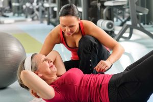 Trainer helping woman do sit up